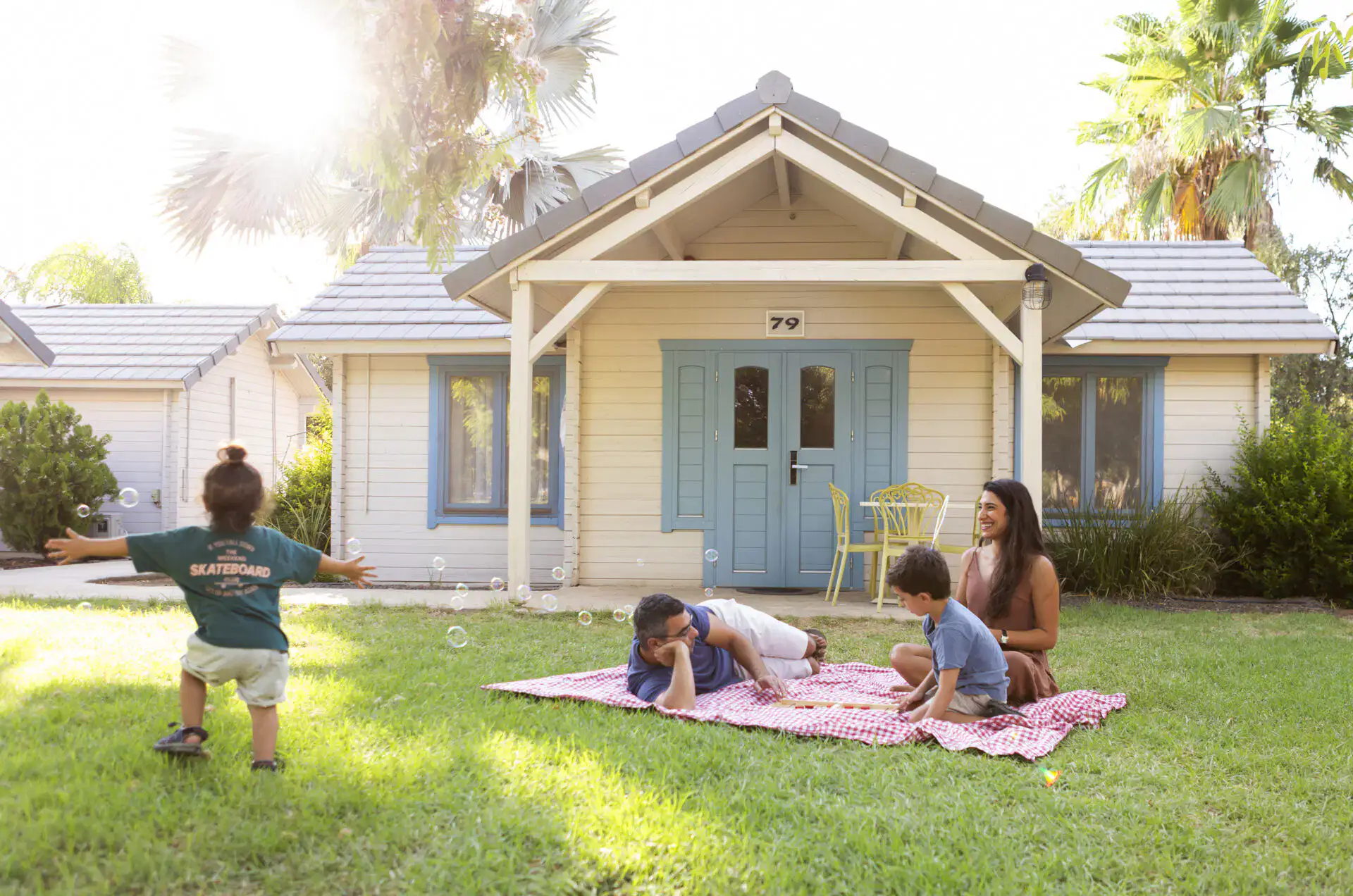 Family enjoying outdoor play on a sunny day in front of a cozy house.